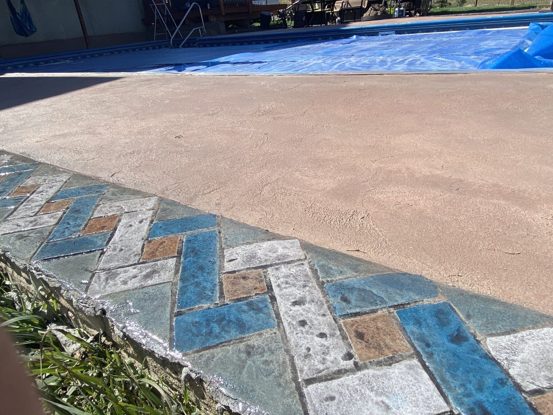 Pool deck with a blue and tan herringbone brick border